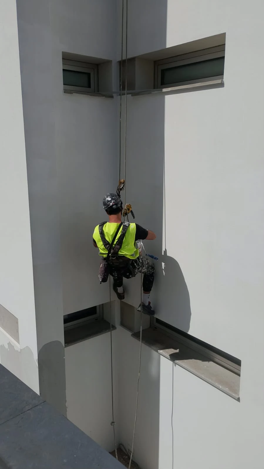 Profissional a executar pintura em rapel numa fachada