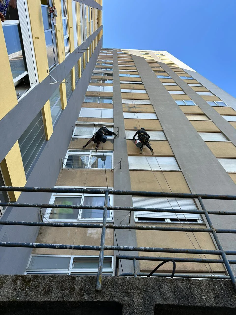 Profissionais em rapel durante pintura de edifício em altura